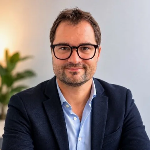 Portrait de Samuel MACHEFER, cofondateur d'OPTIMA FONCIER, portant des lunettes noires, une veste bleu marine et une chemise bleu ciel